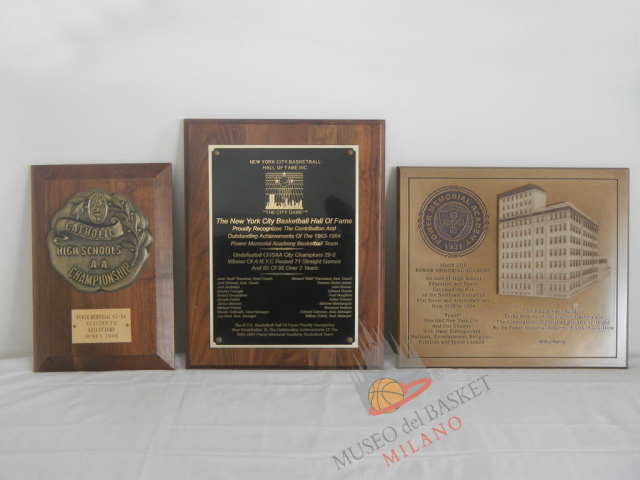 Seconda tranche dei riconoscimenti di Art alla Power Memorial Academy: a sinistra la squadra del 1963/64 entra nella Hall of Fame dell'Associazione delle High School Cattoliche di New York CHSAA per la vittoria del titolo; al centro la targa dell'Introduzione alla New York City Basketball Hall of Fame, oltre che per l'annata 1963/64 anche per la striscia di 71 gare vinte consecutivamente (diventate poi 85 su 86); a destra il riconoscimento eterno della PMA Alumny Association ad Arthur Kenney (co-fondatore dall’Association)...ma con il cognome trascritto male.  (foto Kenney, per gentile concessione del diretto interessato)